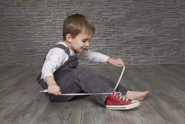 Мальчик завязывает шнурки