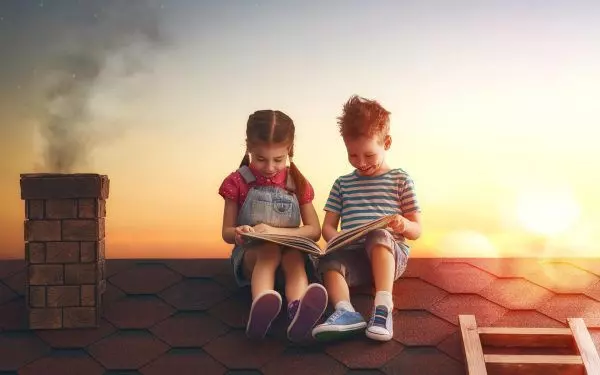 Девушка и мальчик читают книгу на крыше