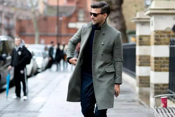Мужчина в пальто и солнцезащитных очках идет по улице