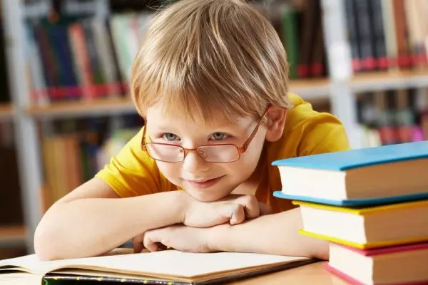 Мальчик в очках читает книгу