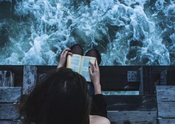 Девушка читает книгу одна у реки