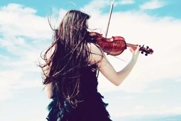 Девушка играет на скрипке на скале
